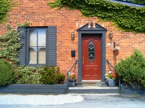 A red door with beveled glass insert surrounded by Georgian style framing.
