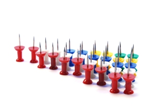 Push pins or tacks with coloured heads, lined up in a triangular formation.